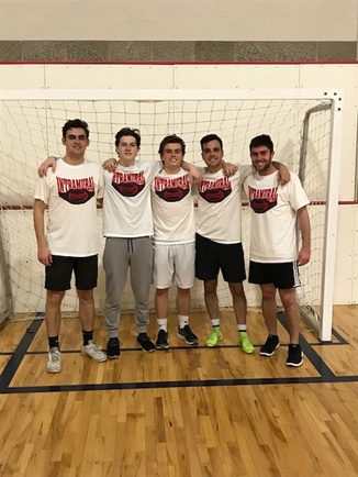 Fraternity League indoor soccer team champions pose in front of the goal in their intramural champion shirts.
