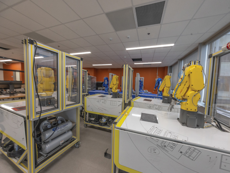 Robotics lab in the Advanced Manufacturing Workforce and Innovation Hub with multiple yellow and blue robot arms