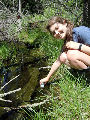 Rachel Pilla collects a water sample in the field.