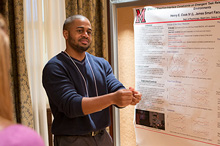 student talking in front of research poster