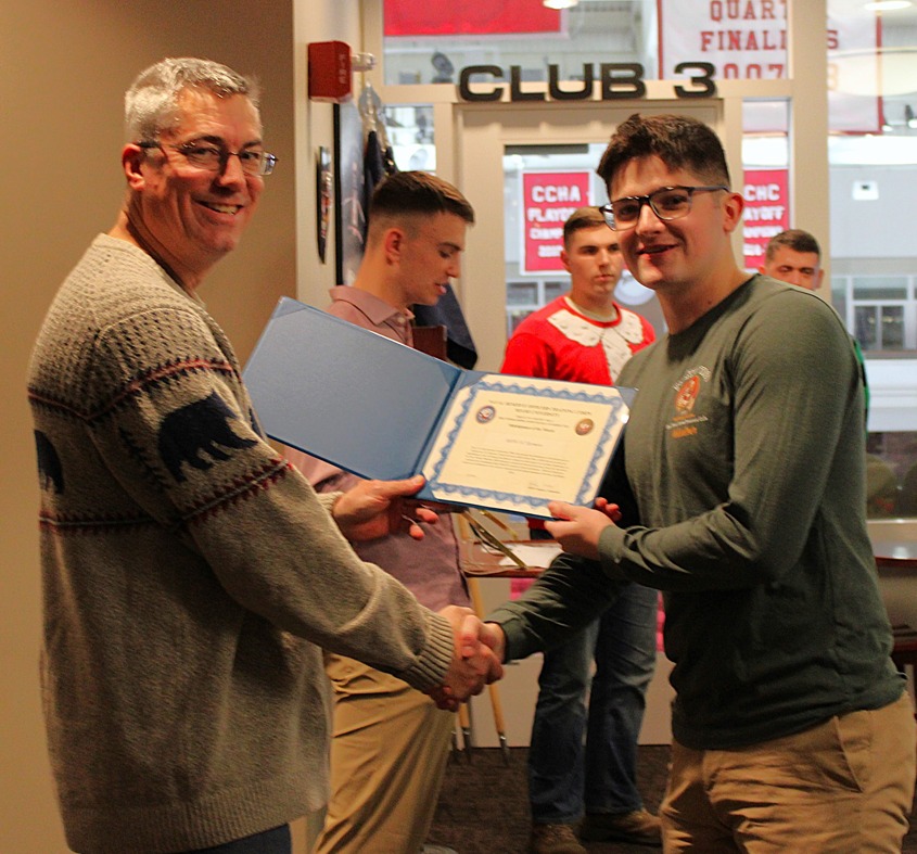 Midshipmen Aidan Sizemore (right) accepts award from Commanding Officer, Captain Jeffrey Lamphear (left) at the midshipmen holiday party.
