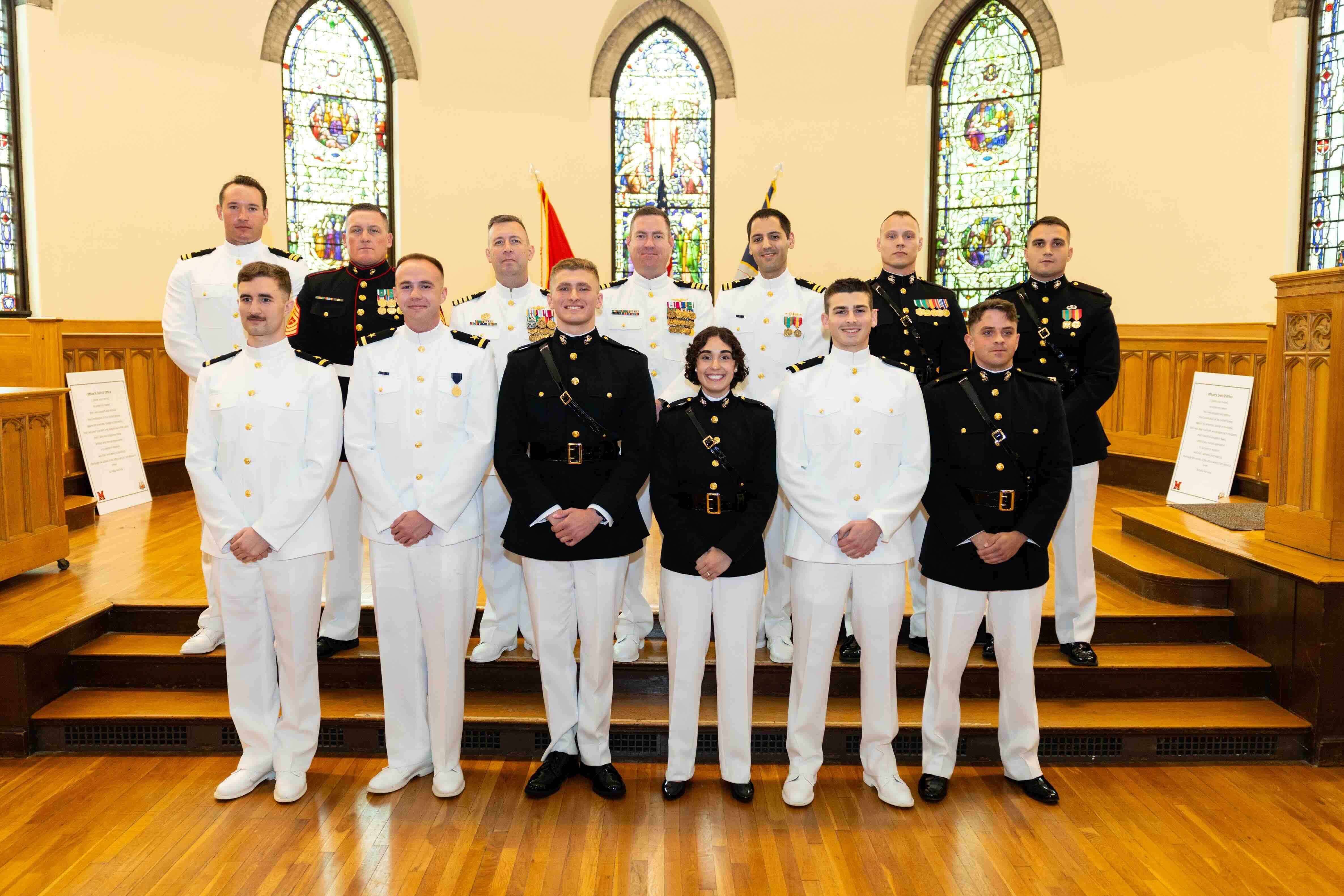 2026 Commissioning Ceremony graduates sitting in a line on the stage.