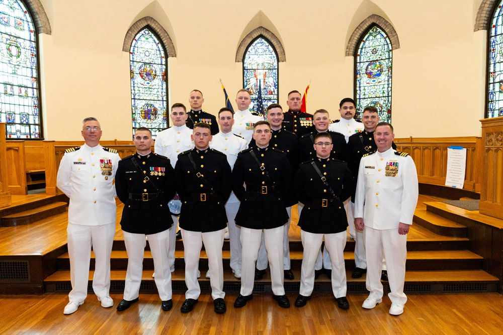 2025 Commissioning Ceremony graduates sitting in a line on the stage.