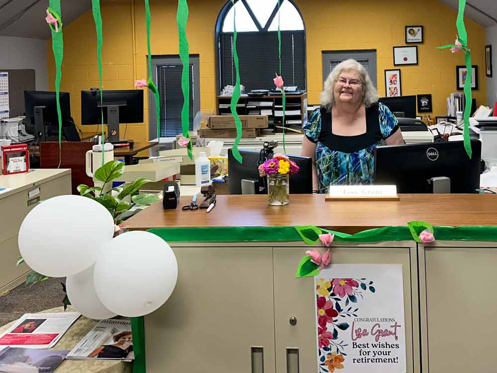 Lisa Grant smiling on her last day at Scripps, her desk decorated with balloons and streamers.