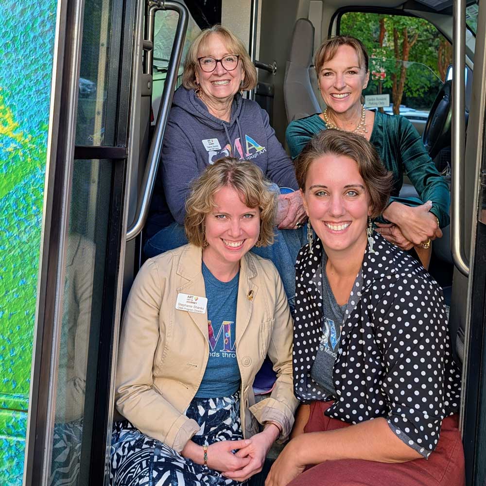 Four women pose on the bus steps. 
