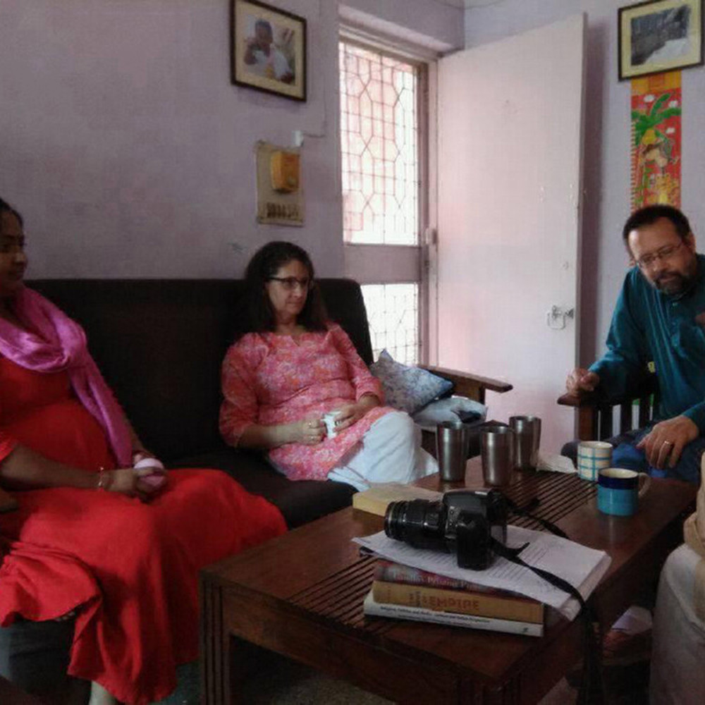 Dr. Mark Peterson sits with a group of Indian women, having a conversation.