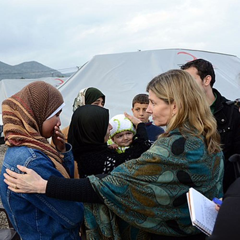 Women comfort refugees at a camp.