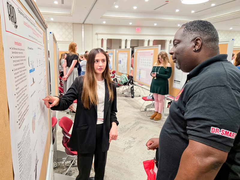 student explaining a research poster to a professor