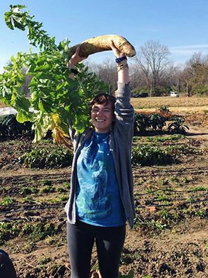 Marla Guggenheimer hoists a large root vegetable at the Institute for Food's organic farm.