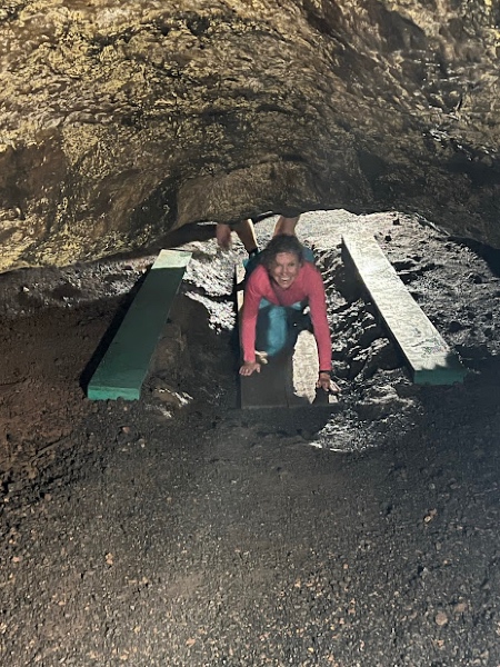 Christie Miller crawling through a dirt tunnel.