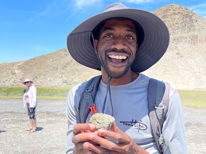 A Baja student looking at a rock