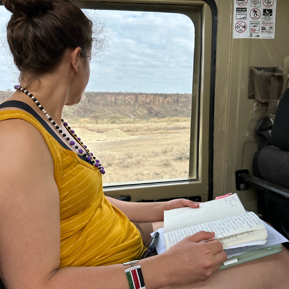 A student in a truck looking out the window with a book in her lap.