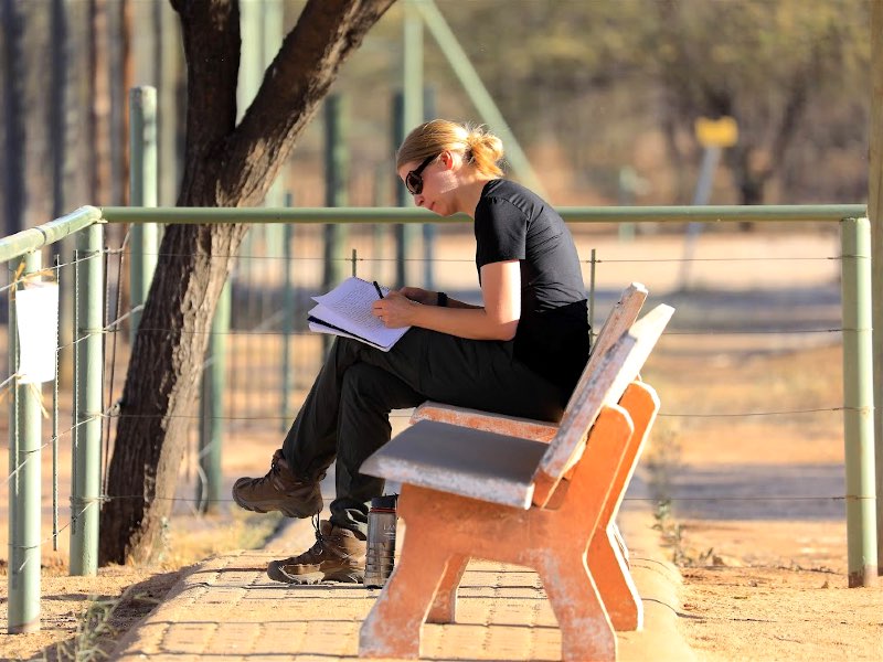 A student sitting on a bench taking notes for class