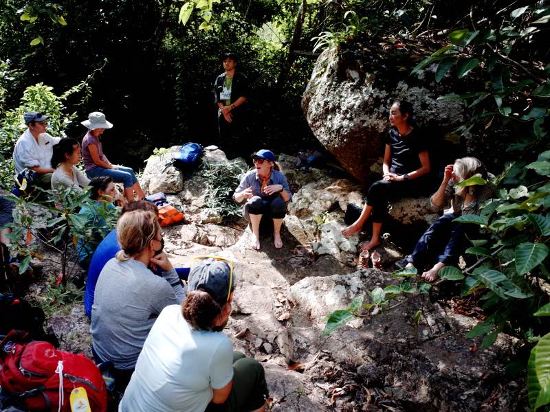 A group discussion next to a rock outcrop