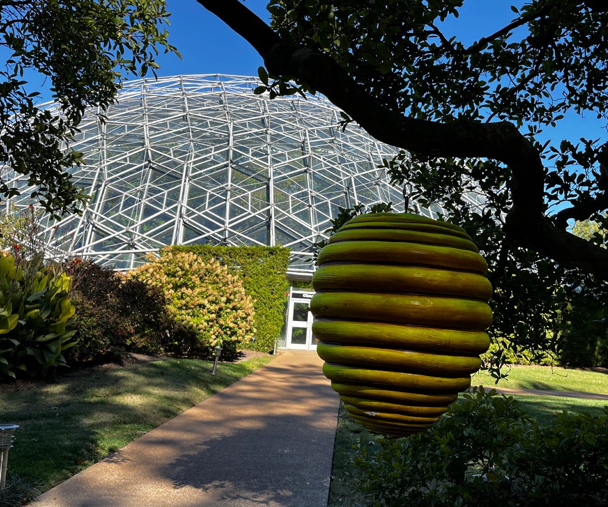 Ceramic honeybee hive with a large glass done in the background.