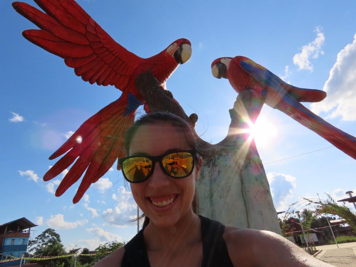 Angie Trumbo standing next to a parrot statue.