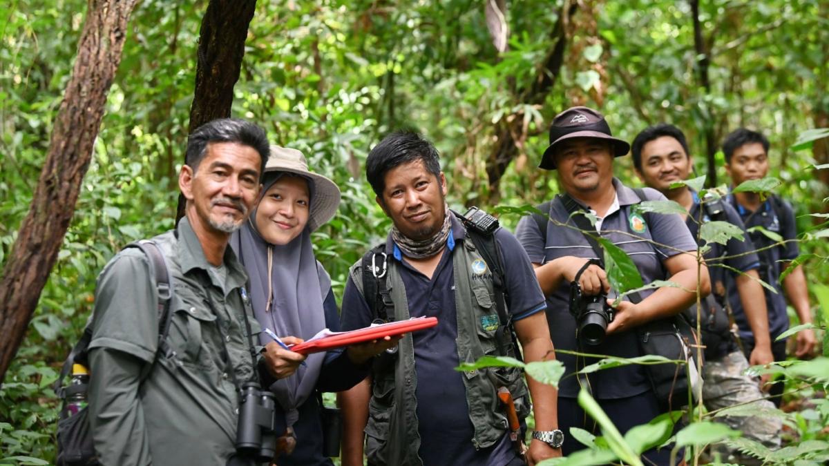 HUTAN members standing in a forest.