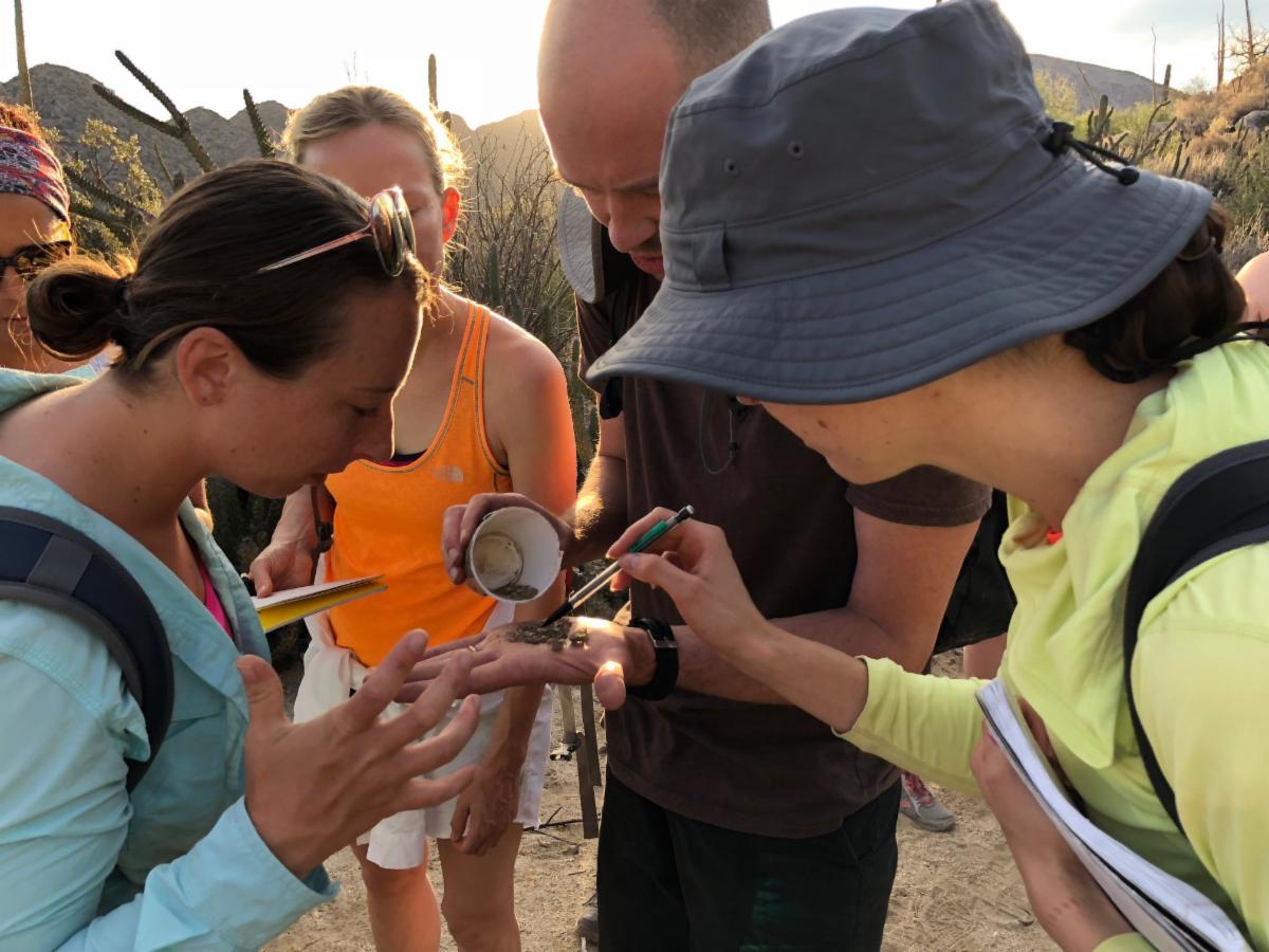 Students gathered together looking at soemthing in another students' hand.