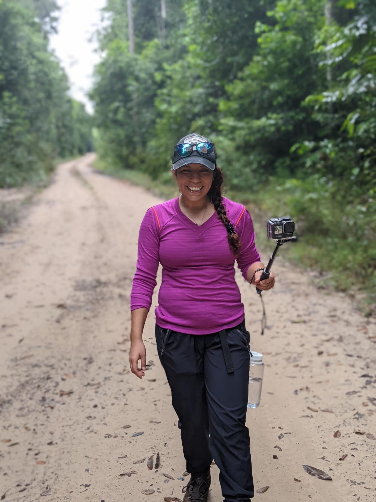 A student with a camera smiling to camera.