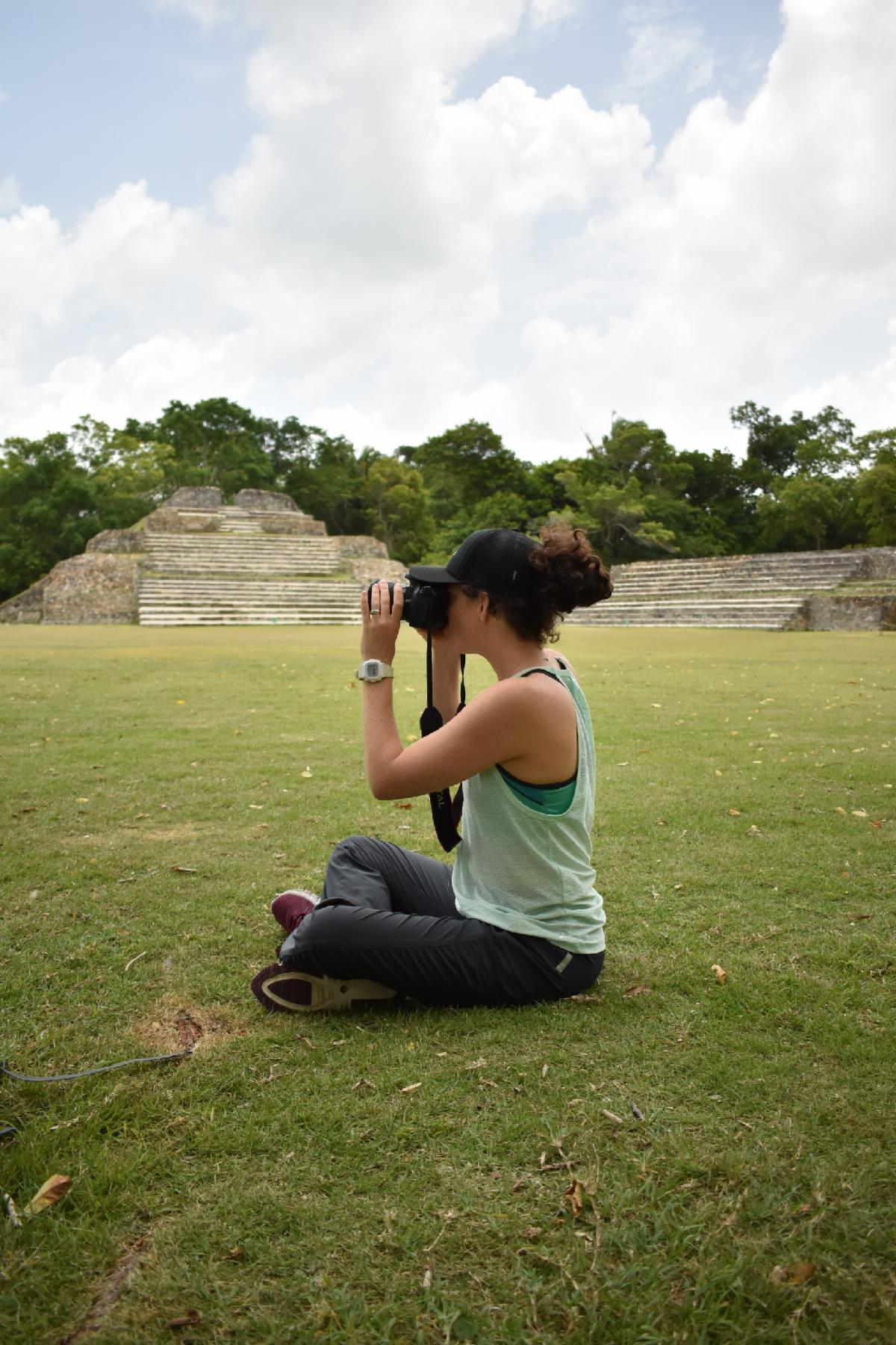 A student sitting on the ground taking a photo.