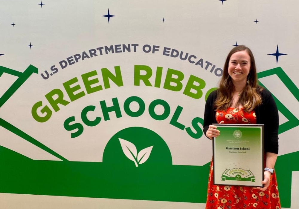 Rachel Arbor standing in front of a wall which states U.S. Department of Education, Green Ribbon Schools.