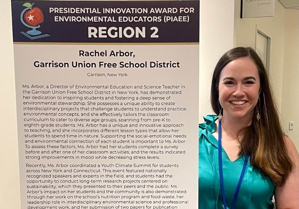 Rachel Arbor standing in front of a presentation board that describes her background in education and the school district she currently teaches at.