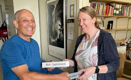Bob Applebaum and Heather Menne smile as they switch their office name plates as they transition the director role.