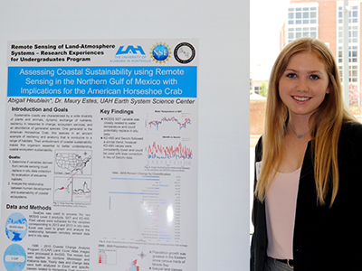 Abby Heublein stands beside a poster summarizing her research results.