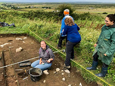 Faith Walker works on her first site in Ireland (2018), a Bronze Age to Early Medieval era tomb. She had just found an important glass bead artifact.
