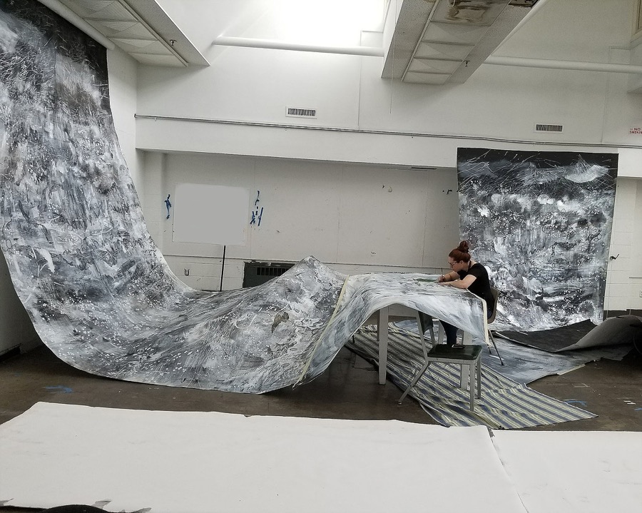 Amy Schissel working on a large curtain-like artwork in her studio