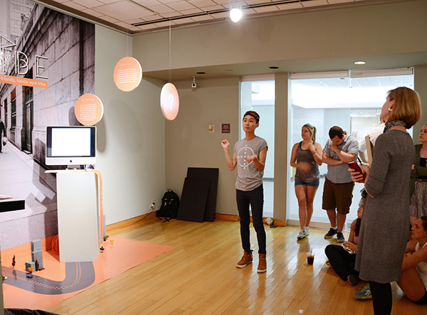 A student artist explains his work of floating orbs to a crowd