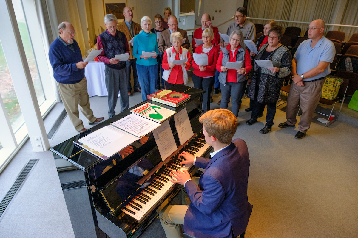 People sing carols near the piano as Jens Bartel plays