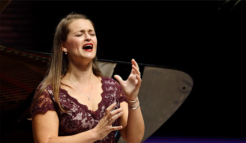 Mezzo Soprano singer Megan Moore image of her singing in front of a grand piano