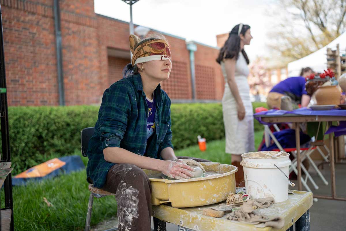 Student creating pottery blindfolded