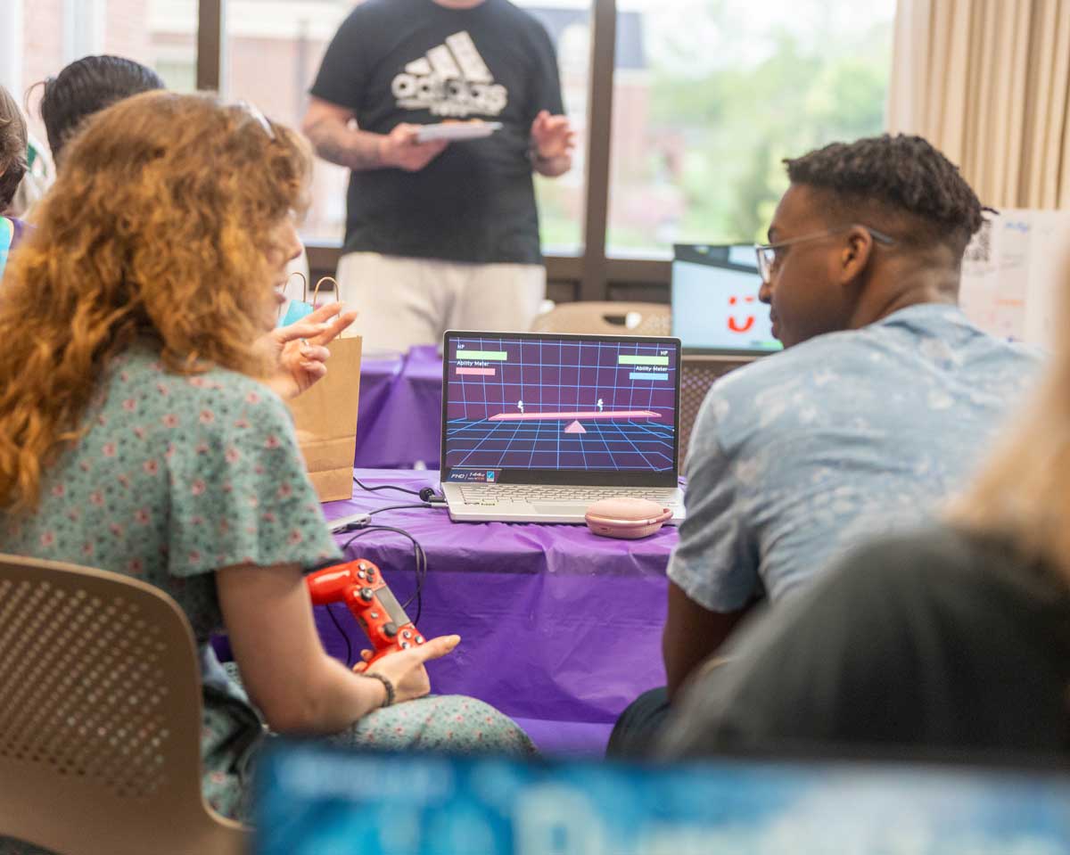 Two students playing a game on a laptop.