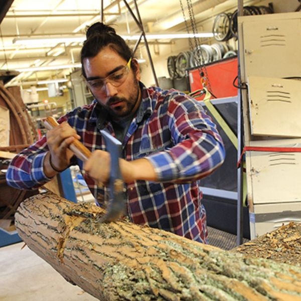 student carving a sculpture out of wood