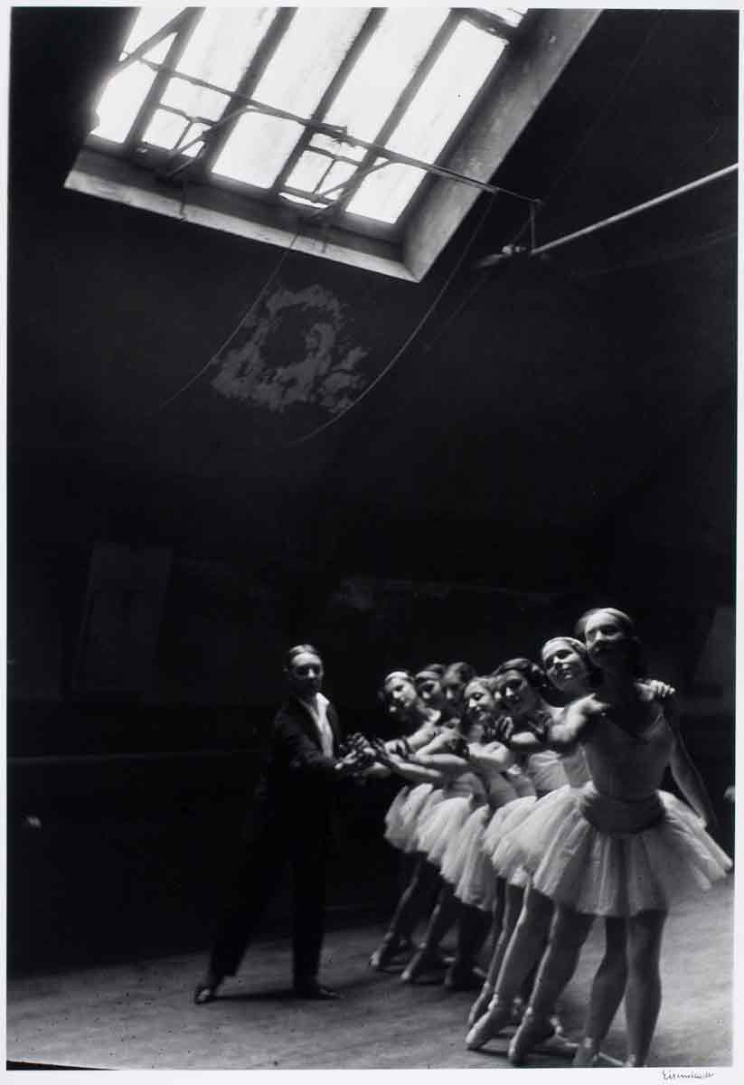 ballerinas practicing in a dark room with a window above