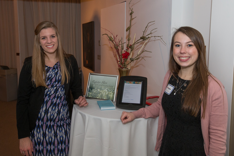 Two student workers pose near a registration book at the Art Museum