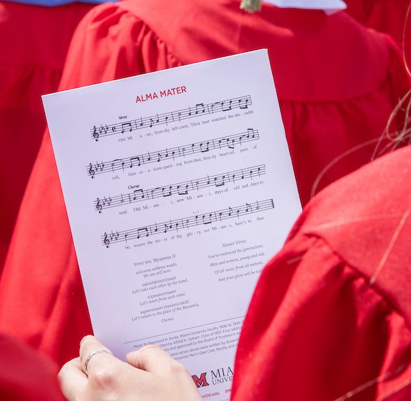 student holding program held with alma mater music and lyrics featured
