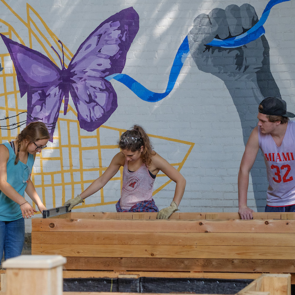 three students building a raised garden