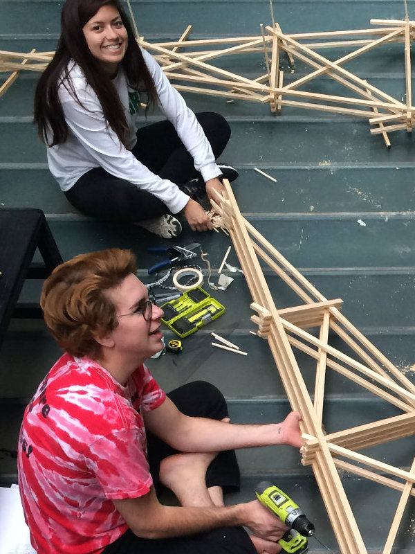 two students assembling a large scale wooden model