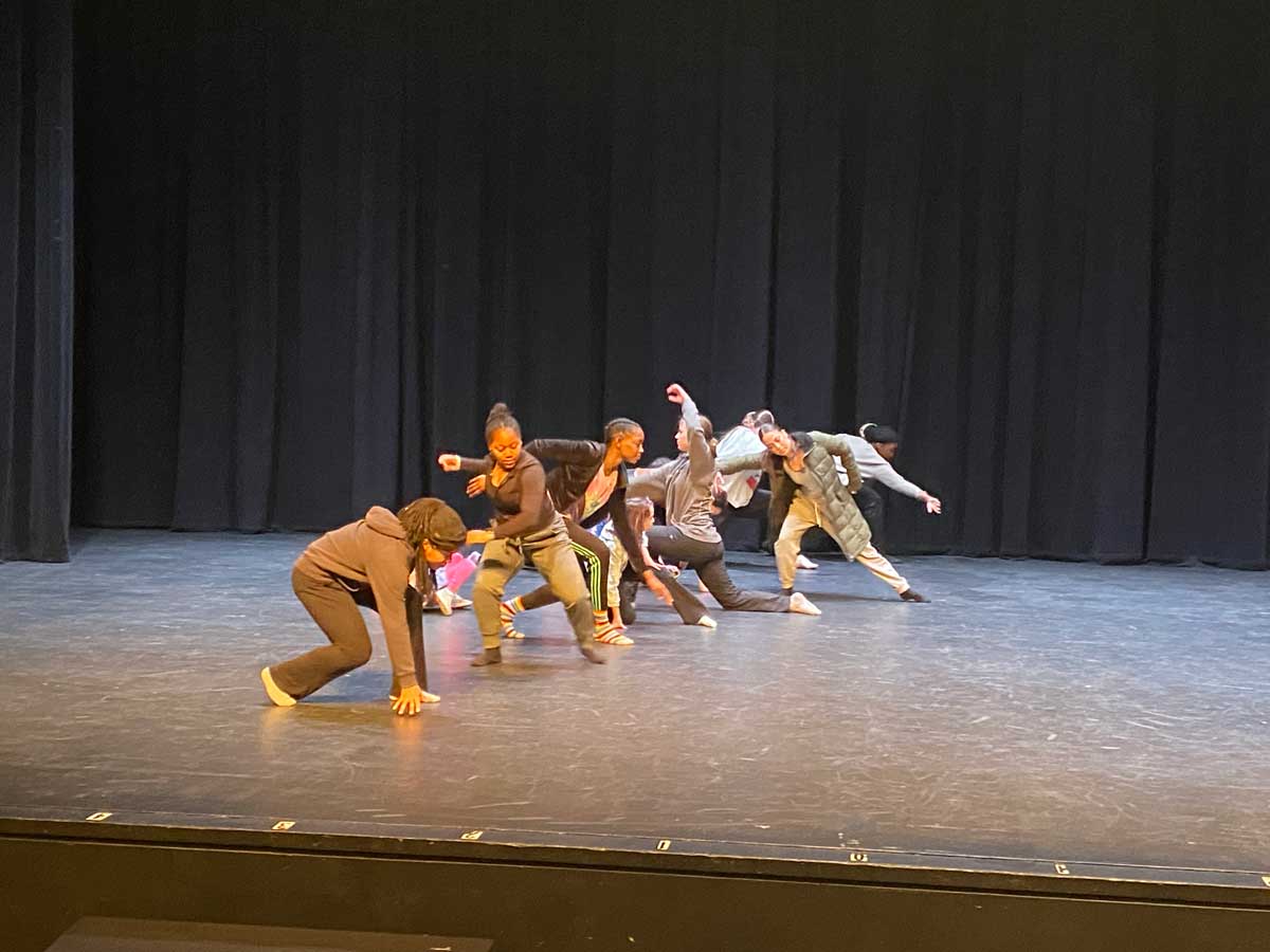 multiple students on stage practicing a similar movement in a line