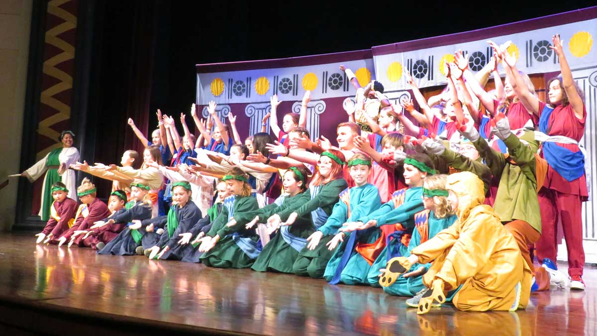 a side view of all drama camp participants and leaders on stage waving to audience