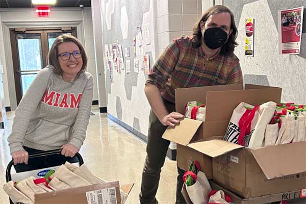 Dr. Stephanie Danker and Dr. Luke Meeken haul swag bags down to the registration table from their offices.