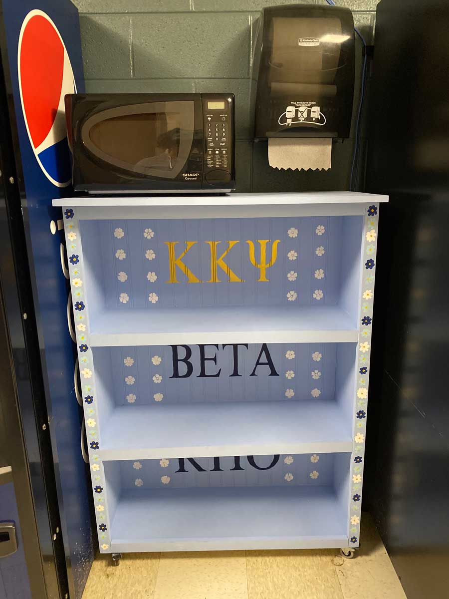 The finished and decorated music shelf installed between vending machines in Presser Hall, now housing a microwave on top.