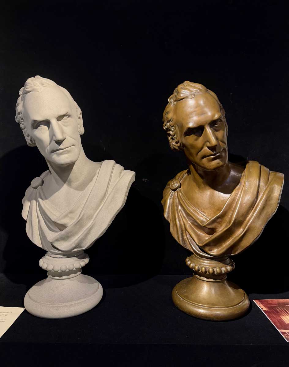 Two sculpted busts of Miami University’s first president, Robert Hamilton Bishop—one white plaster and one bronze—displayed side by side against a dark background.