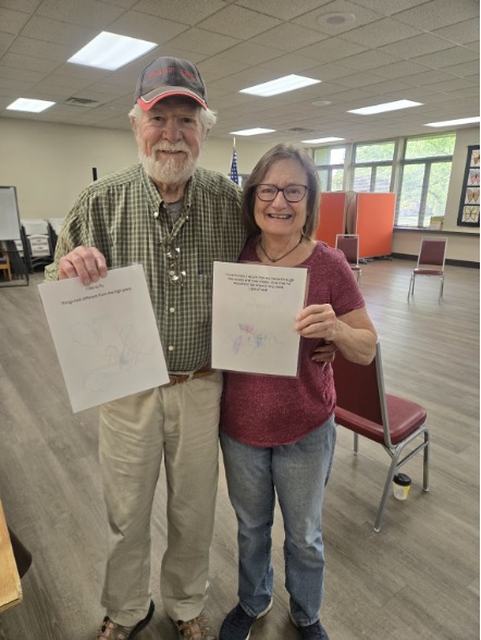 Oxford Seniors participants hold preschoolers’ illustrations created for their collaborative art and literacy picture book project.