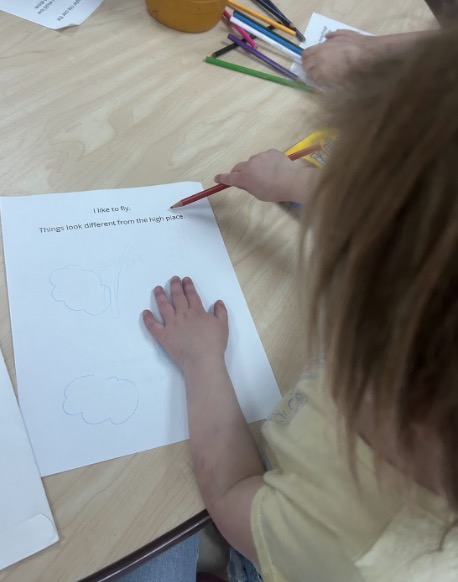 A preschooler colors an illustration for a story in a community art and literacy partnership.