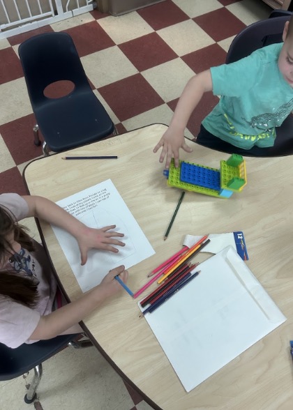 Preschoolers draw story illustrations during a collaborative picture book activity.