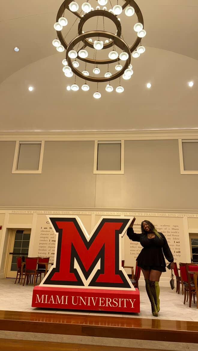 Lady posing near large M under chandelier 